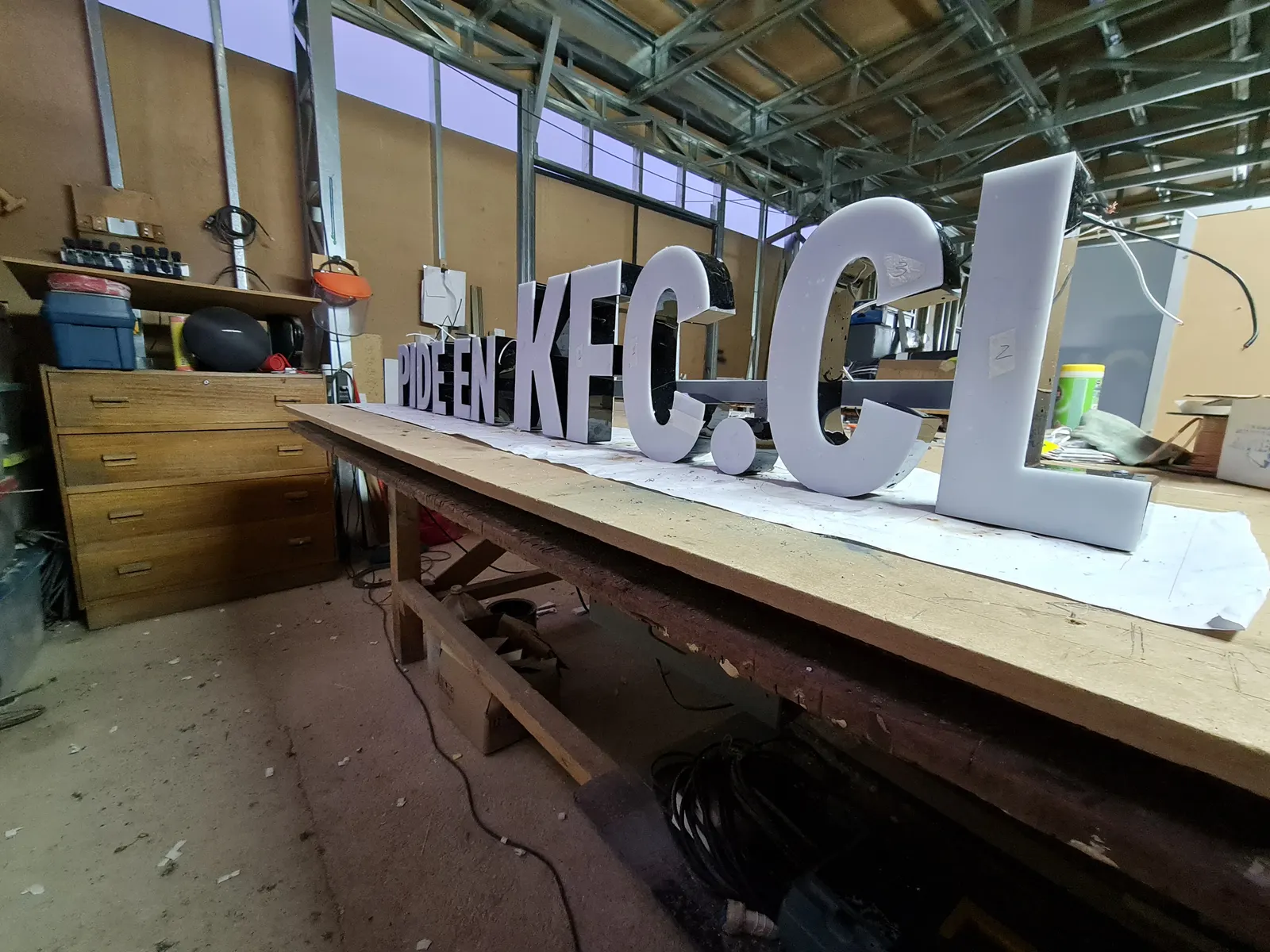 Letras PIDE EN KFC.CL armadas en el taller